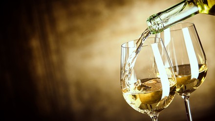 Weingläser die mit Weißwein gefüllt werden
