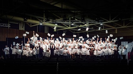 junge Köche werfen auf einer beleuchteten Bühne ihre Mützen in die Luft