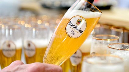 Eine Hand schenkt ein Krombacher Pils ein