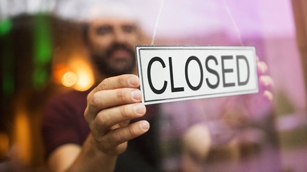 Mann hängt Geschlossen-Schild an Restauranttür