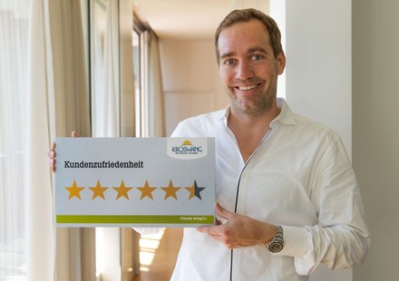 Manfred Kröswang hält Schild mit Kundenzufriedenheit hoch