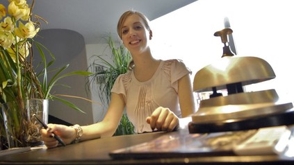 Eine gutgelaunte Empfangskraft an der Rezeption eines Hotels