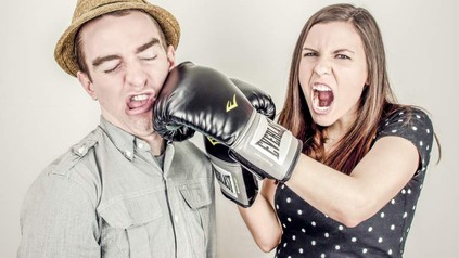 Frau boxt Mann mit Boxhandschuh ins Gesicht