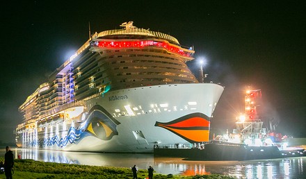 Ein beleuchtetes AIDA-Schiff bei Nacht.