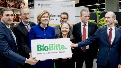 Julia Klöckner und weitere Politiker auf der Messe Biofach halten ein Kampagnenschild mit dem Schriftzug "BioBitte"