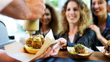 Ein Street Food Händler übergibt aus seinem Truck Snacks an die Besucher