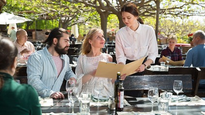 Kellnerin zeigt Speisekarte im Außenbereich