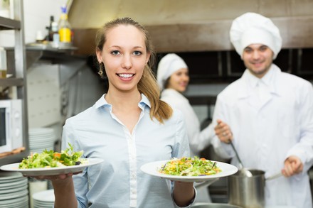 Kellnerin verlässt mit 2 vollen Tellern die Küche