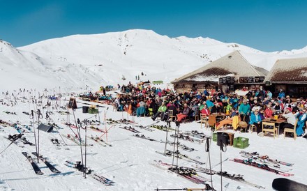 Gute besuchte Skihütte auf einer Piste bei Traumwetter