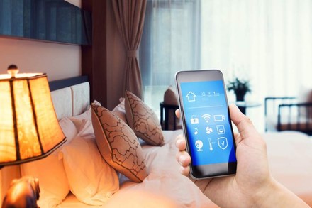 Eine Hand mit Smartphone in einem Hotelzimmer