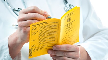 Arzt hält Impfpass in der Hand