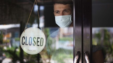 Gastronom steht an der Restauranttür hinter dem „Geschlossen“-Schild