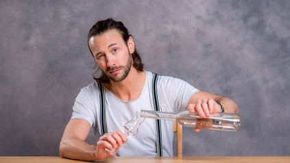 Mann schenkt sich Schnaps in ein Glas