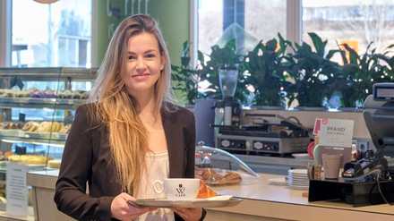 Chiara Wöllhaf, Geschäftsführerin der Wöllhaf-Gruppe am Stuttgarter Airport. (Foto: ©Joachim E. Röttgers)
Junge Frau in einem Coffeeshop mit einem Tablett in der Hand, auf dem eine Kaffeetasse steht
