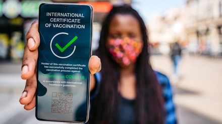 Frau hält Handy mit Impfnachweis in die Kamera