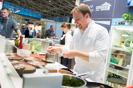 Ein Koch kocht an einemk Messestand für die Besucher
