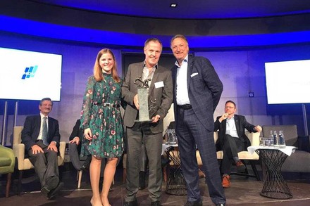 Eine Gruppe Menschen, die auf einer Bühne Urkunden präsentieren