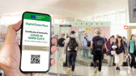 Handy mit geöffnetem Grünen Pass am Flughafen