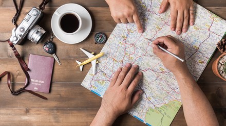 Zwei Menschen, die auf einer Landkarte den Urlaub planen