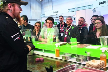 Interessierte Besucher an einem Messestand, bei welchem Fleisch gebraten wird
