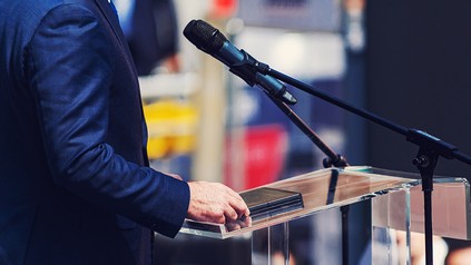 Nahaufnahme eines männlichen Sprechers am Rednerpult, Politiker