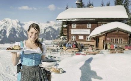 Kellnerin im Winter vor einer Almhütte