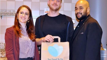 Philip Ibrahim, Hoteldirektor des Mercure Hotel Berlin City, und Franziska Lienert von "Too Good To Go" freuen sich über die 100.000 gerettete Mahlzeit in Berlin. Kunde Robert Reinicke hält sie stolz in Händen.
