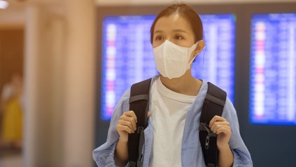 asiatische Touristin mit Mundschutz in einer Abflughalle