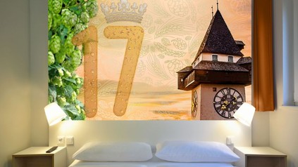 Hotelbett mit Aussicht auf den Grazer Uhrturm