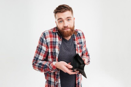 Mann zeigt leeren Geldbeutel und zuckt mit den Schultern