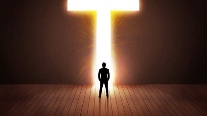 Mann steht vor leuchtendem Kreuz