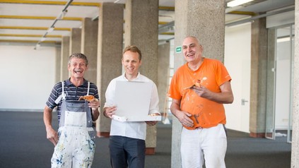 Zwei Arbeiter auf einer Linzer Baustelle freuen sich über die unerwartete Pizza-Lieferung durch Mjam-Geschäftsführer Michael Hagenau