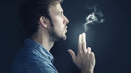 Mann hält Finger wie Pistole. Aus den Fingern tritt Rauch aus