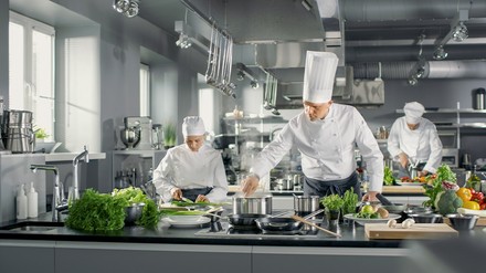 Köche bereiten in der Großküche Essen mit viel Gemüse zu