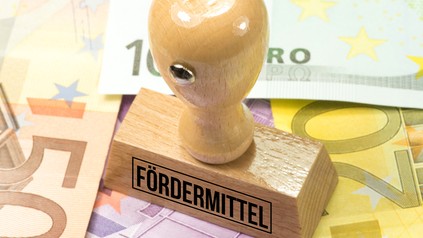 Stempel mit Aufschrift Fördermittel steht auf Euroscheinen
