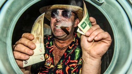 Mann mit Strohhut, Sonnenbrille und Zigarre hält Geldscheine in den Händen
