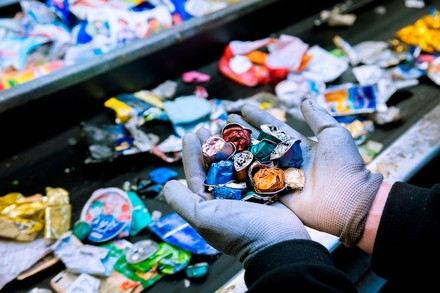 Mann mit Handschuhen hält zerquetschte Kaffeekapseln in der Hand