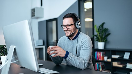 Mann sitzt vor dem PC mit Headset