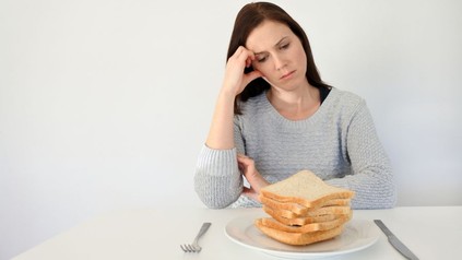 Frau sitzt fragend vor einem Berg Toast