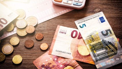 Tisch mit Geldscheinen, Münzen und Taschenrechner