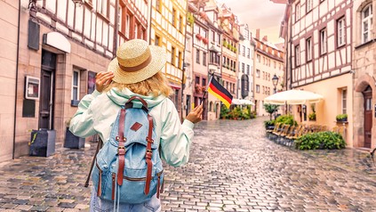 Frau mit Rucksack und Hut in Nürnberg mit einem kleinen Deutschland-Fähnchen in der Hand