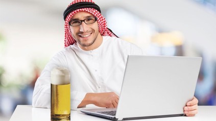 ARaber mit Notebook und einem Glas Bier