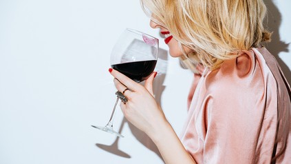 Junge Frau riecht lächelnd am Rotwein