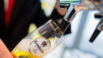 Mann füllt Bier in ein Krombacher Pils Glas