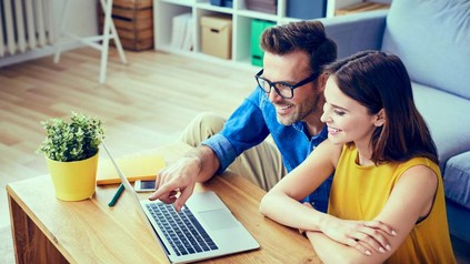 Mann deutet auf Laptop und zeigt Frau etwas auf dem Bildschirm