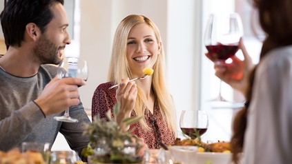 Ein Mann und zwei Frauen essen und trinken im Restaurant