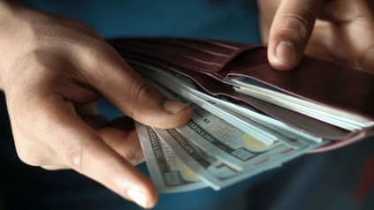 Mann zieht mehrere 100-Dollar-Noten aus der Geldbörse