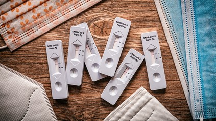 Coronatests auf dem Tisch umringt von Masken