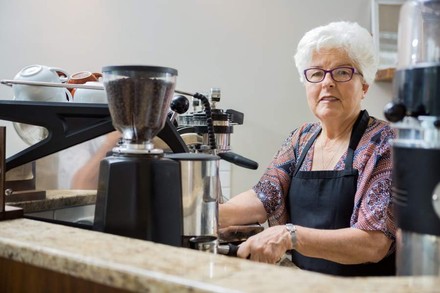 Alte Frau an Kaffeemaschine