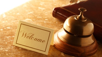 Willkommen-Schild und Klingel auf Tresen